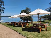 een groep picknicktafels met parasols en een meer bij Stay At Raffertys Resort in Swansea
