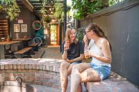 two women sitting on a brick wall holding drinks at Never at Home Kloof Street in Cape Town