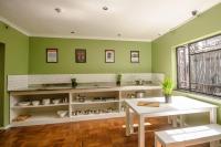 a kitchen with green walls and a white table and a table and a window at Never at Home Kloof Street in Cape Town