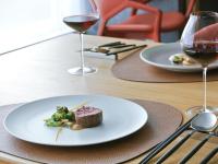 Una mesa con un plato de comida y dos copas de vino. en asbo stay hotel, en Kin