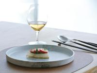 un plato con una pieza de comida y una copa de vino en asbo stay hotel, en Kin