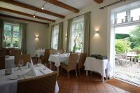 Un restaurante con mesas y sillas blancas y ventanas. en Romantik Hotel Friederikenhof Hotel Restaurant & Spa, en Lübeck