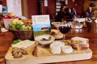 ein Holztisch mit Käse und einem Glas Wein in der Unterkunft Gîte La Grange Du Haut in Saint-Antoine