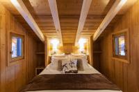 a bed in a wooden room with two windows at Cabane entre terre et ciel in Saint-Nicolas-la-Chapelle