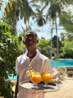 a man holding a tray with two drinks on it at The Nest Tropical Oasis Resort in Paje