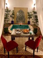 a living room with a table and two chairs and a pool at Riad FARASHA in Marrakech
