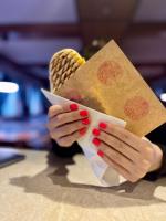 una mujer con esmalte de uñas rojo sosteniendo un pedazo de comida en M1 Laczházy Hotel Coffee & More, en Mocsa