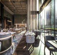 a restaurant with tables and chairs and large windows at voco Melbourne Central in Melbourne