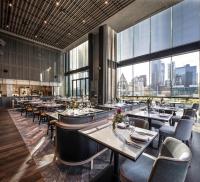 a restaurant with tables and chairs and large windows at voco Melbourne Central in Melbourne