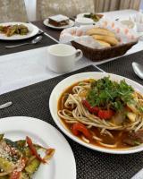 a table with a plate of spaghetti and a bowl of food at CasaBrava at RadugaWest in Koshkolʼ