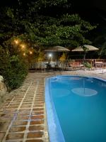 Una piscina azul por la noche con mesas y sombrillas. en Cabañas Between Hills, en San Alfonso