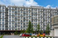 ein großes weißes Gebäude mit auf einem Parkplatz geparkten Autos in der Unterkunft Zenith Suites Cameron in Tanah Rata