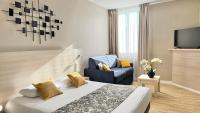 Una habitación de hotel con una cama y una silla azul. en Hôtel Helvétique, en Niza