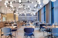 uma sala de jantar com mesas, cadeiras e lustres em Novotel Hamburg Central Station em Hamburgo