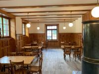 Un restaurante con mesas y sillas de madera y ventanas. en Albergo Ristorante Stazione Cavaglia, en Poschiavo