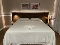 Una gran cama blanca con una camisa blanca. en Hotel Nelo, en Jaraguá do Sul
