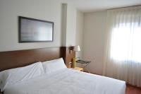 Un dormitorio con una cama blanca y una ventana. en Hotel Palacio Congresos, en Palencia