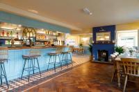a bar with chairs and a fireplace in a restaurant at The Wittering in West Wittering
