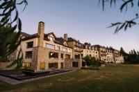 un gran edificio con un patio de césped delante de él en Loi Suites Chapelco Hotel, en San Martín de los Andes