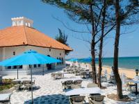 Un grupo de mesas y sillas con una sombrilla en la playa. en Villa La Bella Phan Thiet, en Phan Thiet