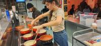 a woman is preparing food in a kitchen at Freeride Hostel in Les Crosets
