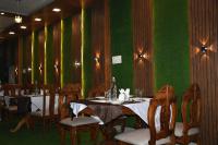 una sala da pranzo con tavoli e sedie e pareti verdi di Hotel Maharaja Palace a Bhagalpur