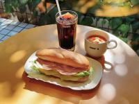 東京にあるアパホテル〈蒲田駅前〉のテーブルの上の飲み物の横の皿の上のサンドイッチ