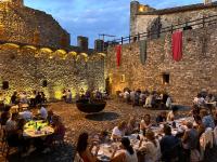 un gruppo di persone seduti ai tavoli di fronte a un castello di TENUTA CASTEL DELL'AQUILA a Gragnola