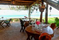 Garden House - Ilha do Guajiru في إيتاريما: مطعم مع طاولات وكراسي وإطلالة على المحيط