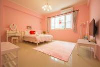 a bedroom with pink walls and a bed and a mirror at Ciao Life B&amp;B in Taitung City