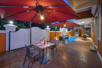 un patio con mesa, sillas y sombrillas rojas en Vega Suites with Private Indoor Pool, en Colva