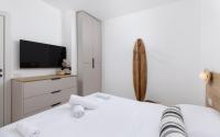 ein weißes Schlafzimmer mit einem Bett und einem Fernseher in der Unterkunft אורה דירות אירוח -נץ 9- דירות נופש איכותיות לנופש שקט ואקסלוסיבי in Eilat