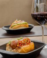 图蓬加托火山House by Casa Septem的平底锅里放着两根热狗，旁边放着一杯葡萄酒。