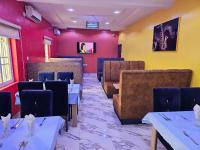 comedor con mesas, sillas y paredes rojas en KayQuin Garden, en Warri