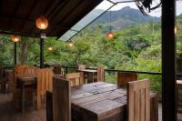 restauracja z drewnianymi stołami i krzesłami oraz widokiem w obiekcie The Glenrock Wellness Nature Resort w mieście Belihul Oya