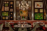 um restaurante com mesas e cadeiras e um lustre em The Carlyle, A Rosewood Hotel em Nova Iorque