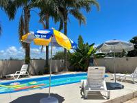 a blue and yellow umbrella and chairs next to a swimming pool at Loft incrível e completo in São Lourenço do Sul