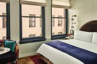 a bedroom with a bed and a chair and windows at Hotel Per La, Autograph Collection in Los Angeles
