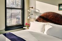 a bedroom with a bed with a wooden headboard and a window at Hotel Per La, Autograph Collection in Los Angeles