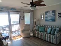 ein Wohnzimmer mit einem Sofa und einem Stuhl sowie einem Balkon in der Unterkunft Shore Tails, LLC in Myrtle Beach