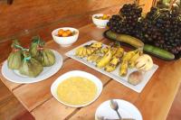 伊基托斯PuraChata Ecolodge的一张桌子上摆放着几盘香蕉和其他水果蔬菜。