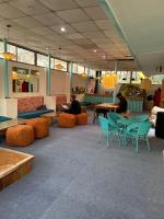 Una habitación con sillas y mesas y gente sentada en las mesas. en Serendipity Hostel & Cats Cafe, en Rishīkesh