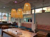 un restaurante con mesa, sillas y lámparas de araña en Serendipity Hostel & Cats Cafe, en Rishīkesh