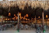 a restaurant with tables and chairs and a straw umbrella at Sunsol Punta Blanca in San Pedro de Coche