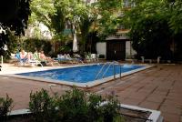a swimming pool with people sitting in chairs around it at Galeón in Sitges