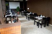 una fila de mesas y sillas en un restaurante en Hotel Orchard Coorg, en Virajpet