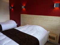 two beds in a hotel room with red walls at La Godinière in Cholet