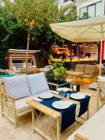 een patio met een bank, tafels en een parasol bij Patron Hotel in Antalya