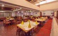un restaurante con mesas y sillas con jarrones amarillos. en Hotel Ger manus Madurai, en Madurai