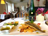 ein Teller Fisch mit Pommes frites und eine Flasche Wein in der Unterkunft Landhotel Laarmann in Lennestadt